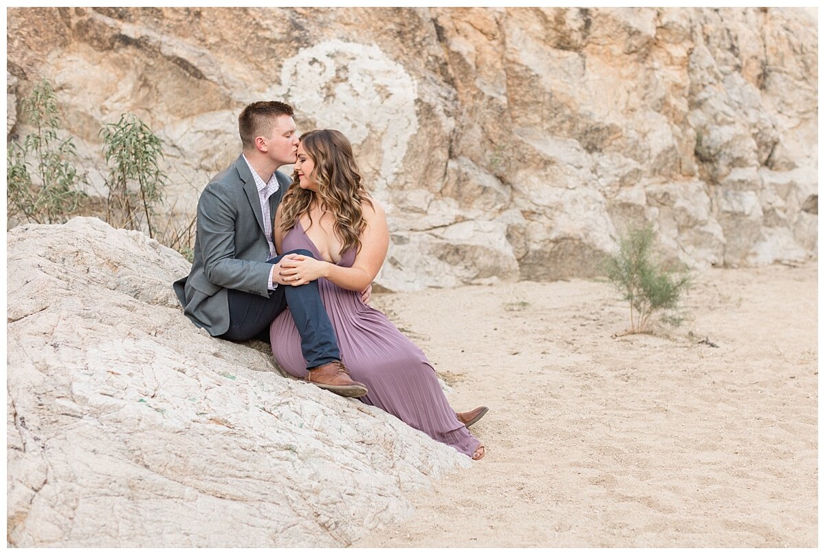 Engaged couple sitting on a rock in the Tucson desert at their engagement session with Melissa Fritzsche Photography.