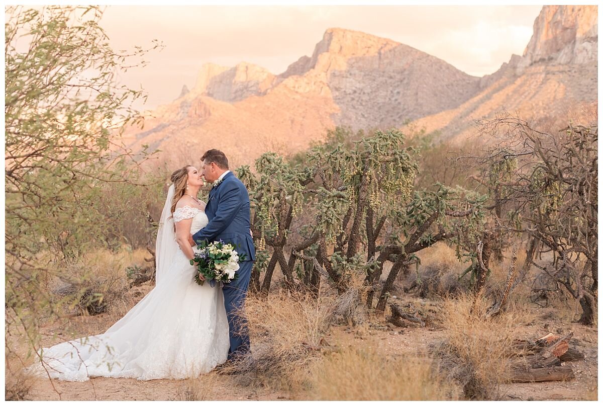 The Buttes at Reflections Wedding Venue. Couple shares a kiss in front of the Pusch Ridge Mountains in Tucson, Arizona at the Buttes at Reflections Wedding Venue.