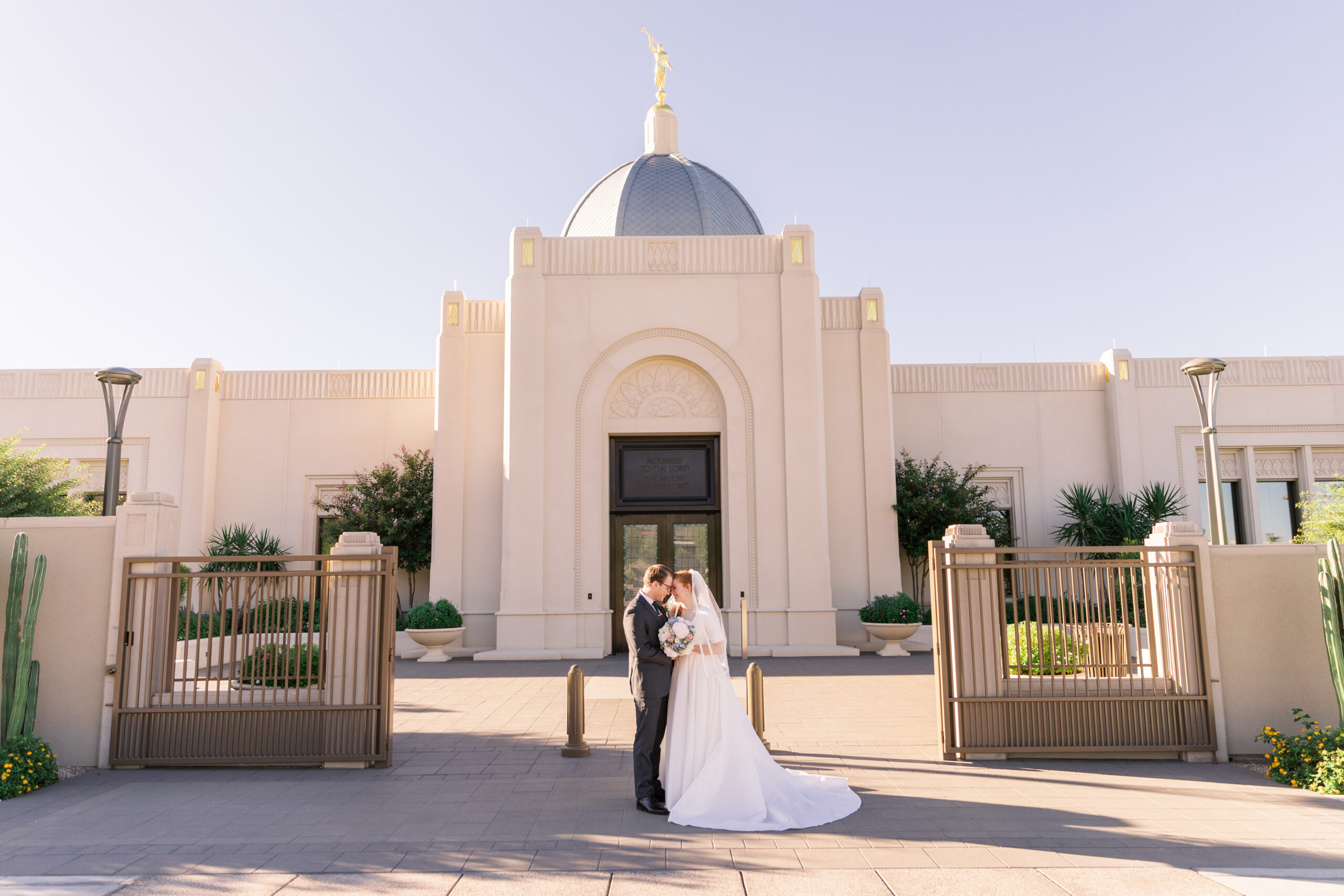 Couple posing in front of the Tucson Temple on their wedding day.