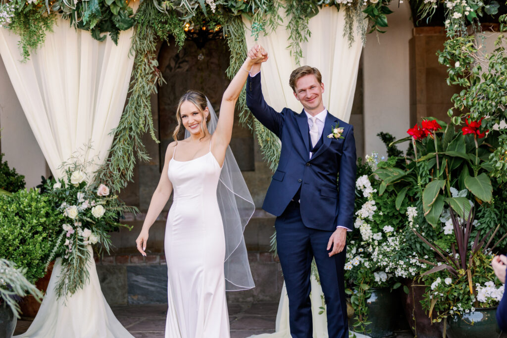Couple holding hands in air celebrating after wedding ceremony at Stillwell House.
