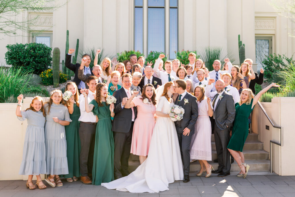 Family and Friends stand on the Tucson Temple Stairs and Cheer for the Bride and Groom as they share a kiss on their wedding day.