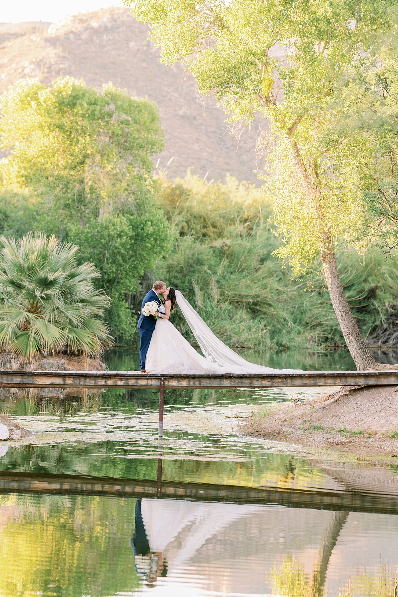 Bride and Groom kiss while surrounded by the towering trees at Tanque Verde Ranch Wedding Venue in Tucson, Arizona