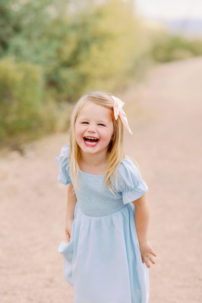 Toddler girl laughs towards the camera during family photos in Arizona.