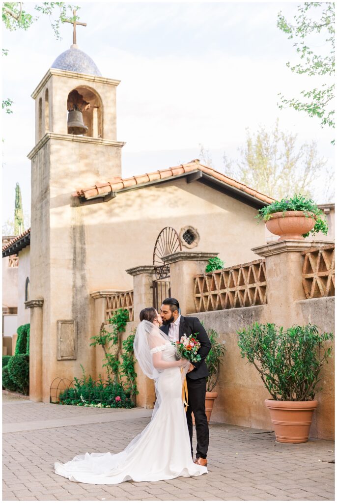 Bride and groom kissing outside the Tlaquepaque Chapel in Sedona on their wedding day.