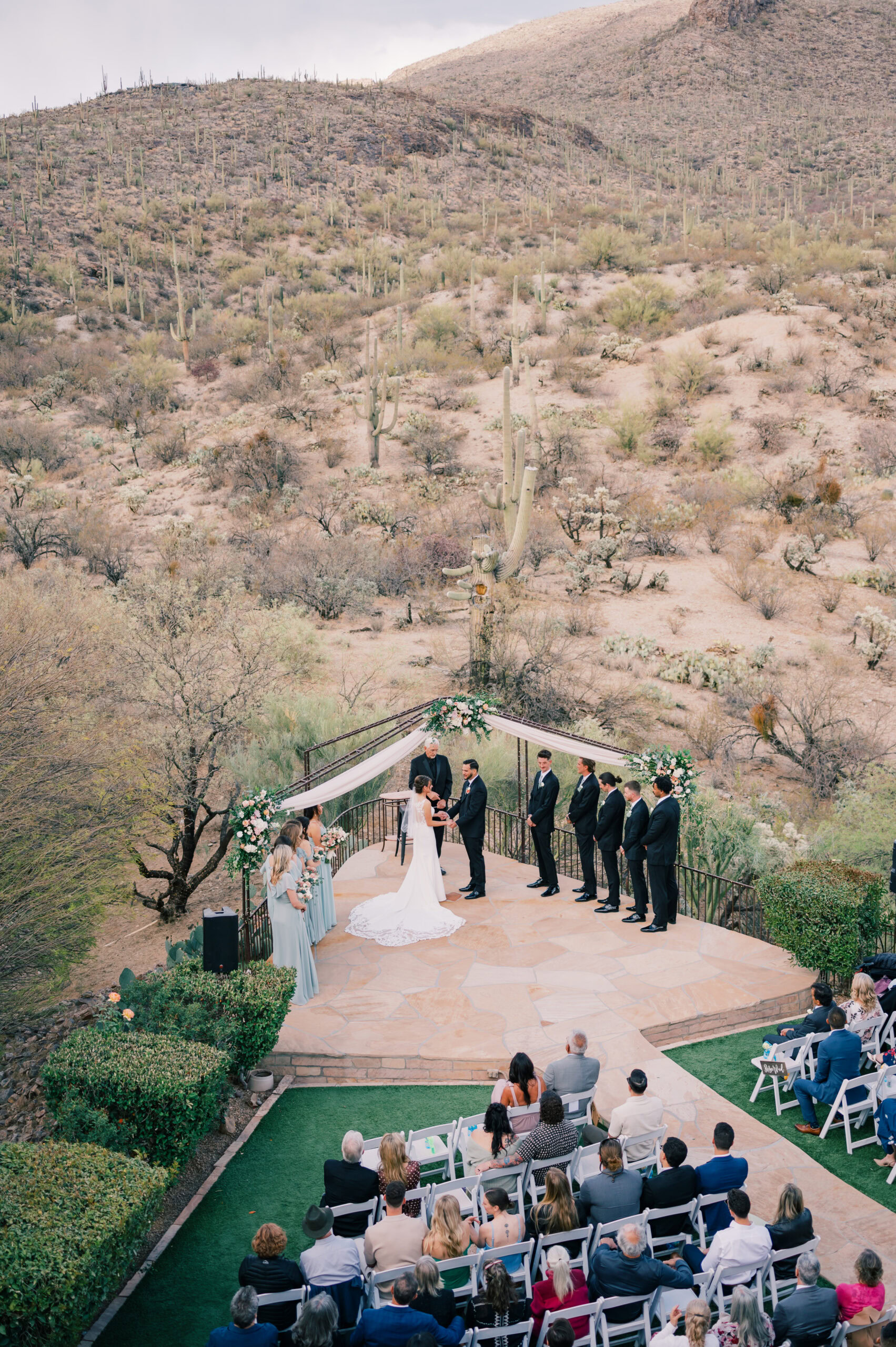 Couple exchanging vows at Saguaro Buttes, surrounded by loved ones and panoramic desert views in Tucson, Arizona